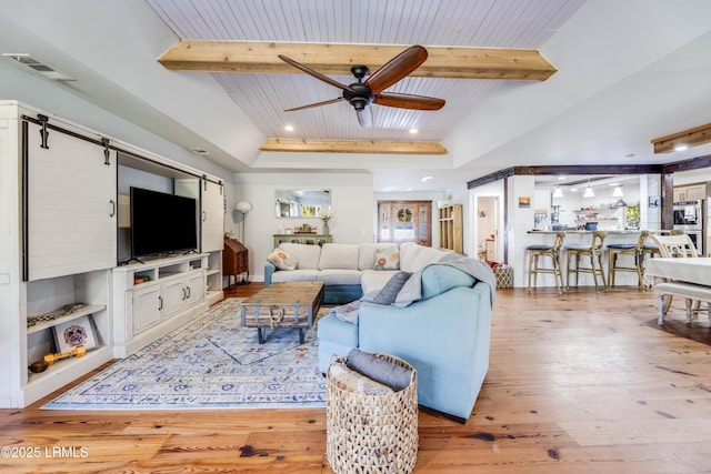 living room featuring built in shelves, beam ceiling, light hardwood / wood-style flooring, and wooden ceiling