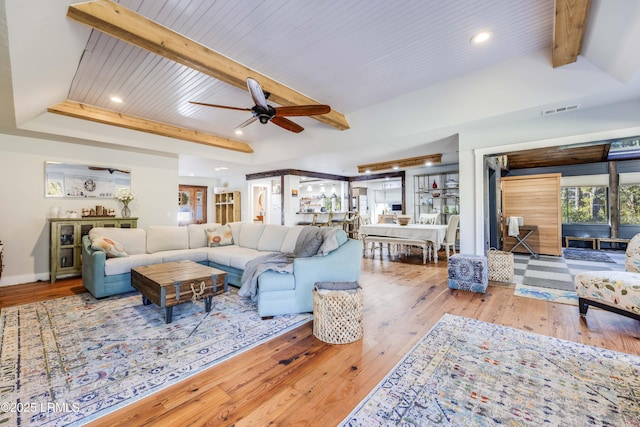 living room with ceiling fan, beamed ceiling, light hardwood / wood-style floors, and wooden ceiling