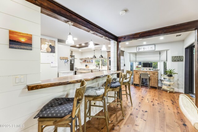 kitchen with wall chimney range hood, appliances with stainless steel finishes, backsplash, white cabinets, and decorative light fixtures