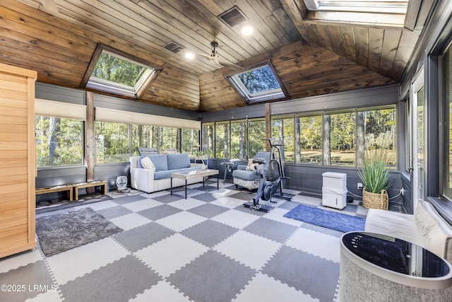 sunroom featuring a healthy amount of sunlight, ceiling fan, wooden ceiling, and vaulted ceiling with skylight