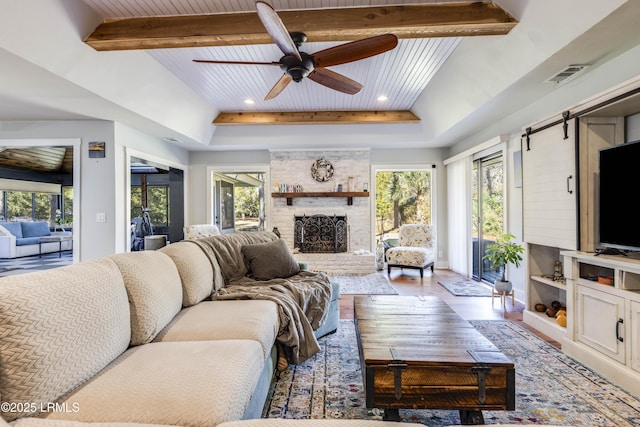 living room with hardwood / wood-style flooring, ceiling fan, a fireplace, wooden ceiling, and beamed ceiling