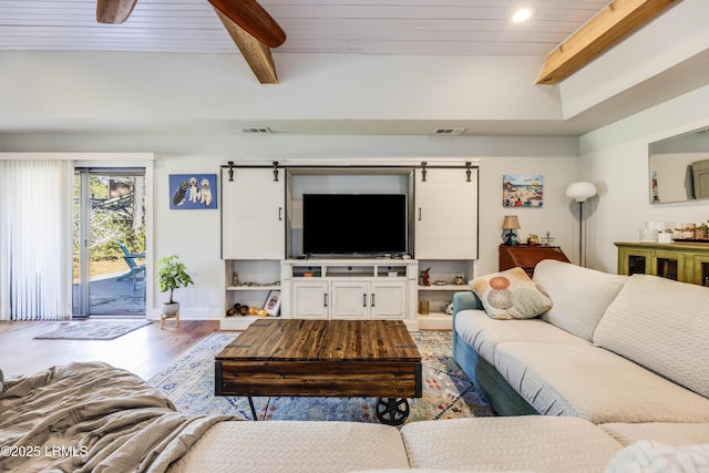 living room featuring beamed ceiling, a barn door, and wooden ceiling