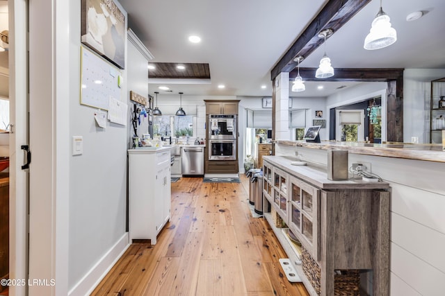 kitchen with white cabinetry, hanging light fixtures, light hardwood / wood-style flooring, and appliances with stainless steel finishes