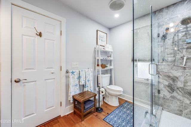 bathroom with wood-type flooring, toilet, and a shower with shower door