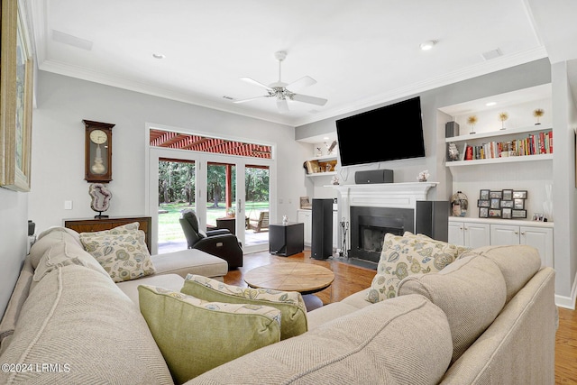 living room featuring ornamental molding, ceiling fan, light wood-type flooring, and built in shelves