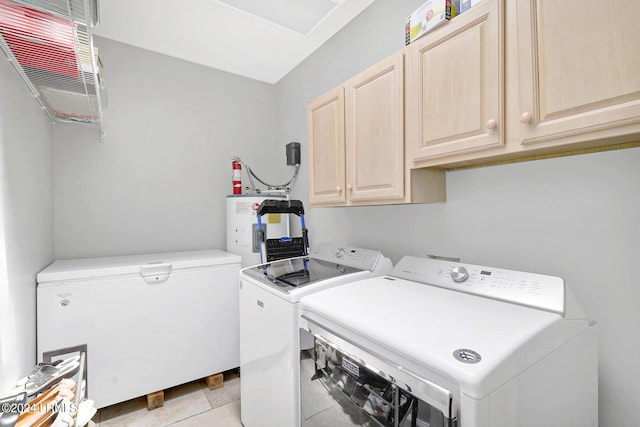 laundry area with electric water heater, light tile patterned floors, washing machine and dryer, and cabinets