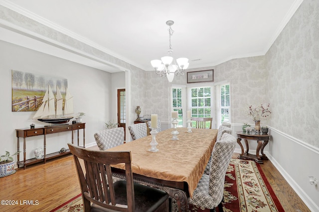 dining space featuring an inviting chandelier, ornamental molding, and hardwood / wood-style floors