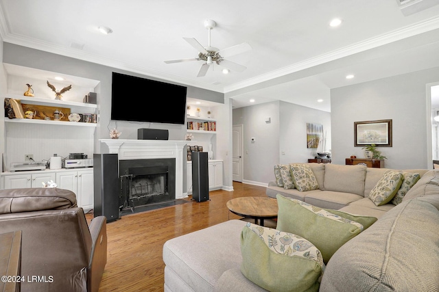 living room with ceiling fan, ornamental molding, built in features, and light hardwood / wood-style flooring