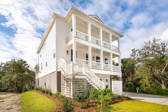 view of front of property featuring a porch, a balcony, concrete driveway, and stairs