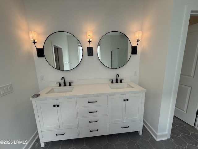 full bathroom with a sink, baseboards, double vanity, and tile patterned flooring