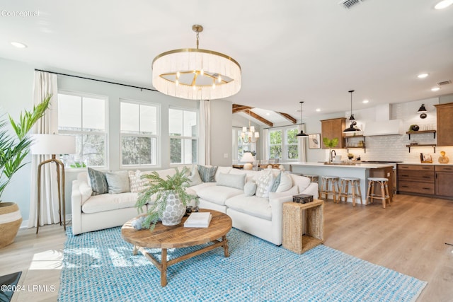 living area featuring vaulted ceiling, light wood-style floors, a notable chandelier, visible vents, and recessed lighting