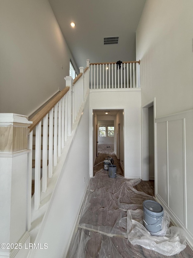 stairway with recessed lighting, visible vents, and a high ceiling