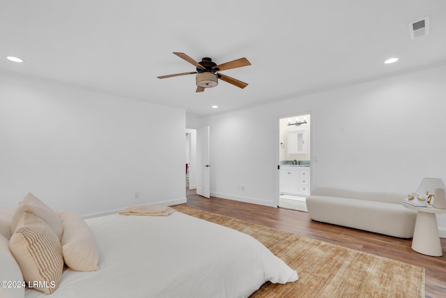 bedroom featuring hardwood / wood-style floors, ensuite bath, sink, and ceiling fan