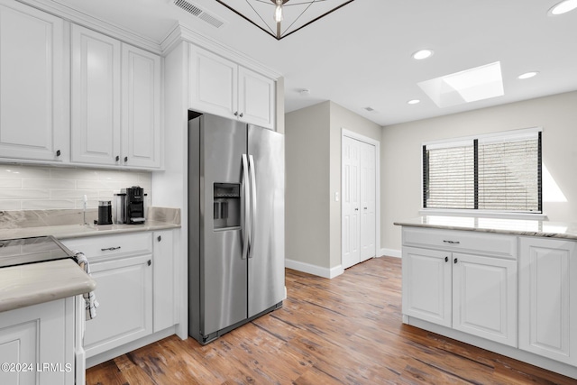 kitchen with stainless steel fridge with ice dispenser, backsplash, white cabinets, and hardwood / wood-style flooring