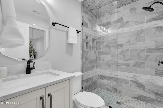 bathroom with vanity, toilet, and a tile shower