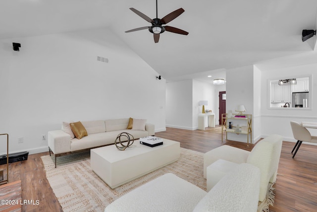 living room with hardwood / wood-style flooring, ceiling fan, a barn door, and high vaulted ceiling