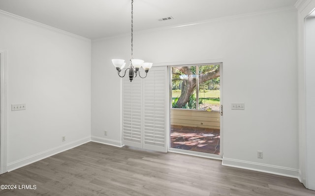 unfurnished dining area featuring crown molding, dark wood-type flooring, and a notable chandelier