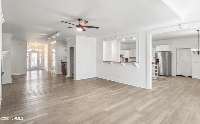 unfurnished living room featuring ornamental molding, ceiling fan with notable chandelier, and light hardwood / wood-style flooring