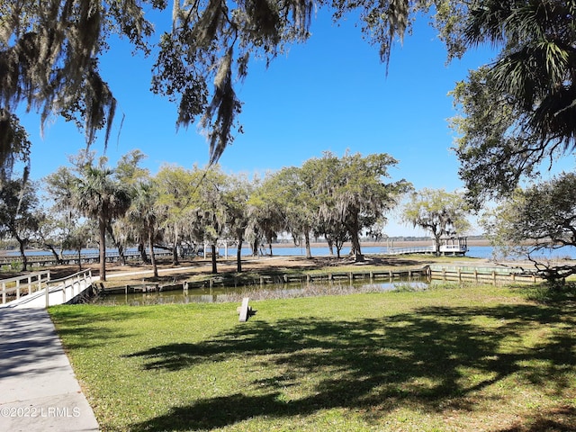 surrounding community with a water view and a lawn