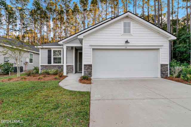 view of front of home featuring an attached garage, central AC unit, stone siding, driveway, and a front lawn