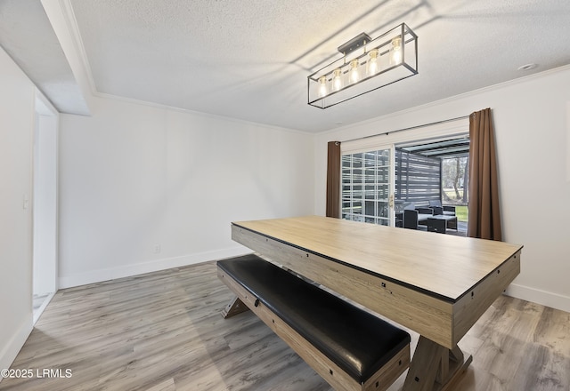 dining space with baseboards, a textured ceiling, ornamental molding, and wood finished floors