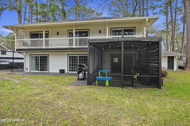 back of house featuring a sunroom, roof with shingles, a yard, and a balcony