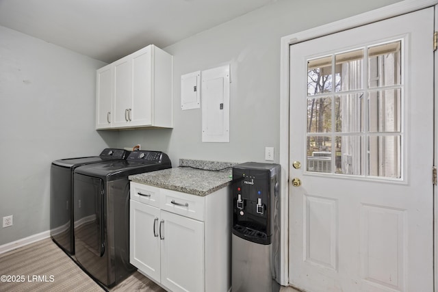 washroom with cabinet space, electric panel, baseboards, independent washer and dryer, and light wood-style floors