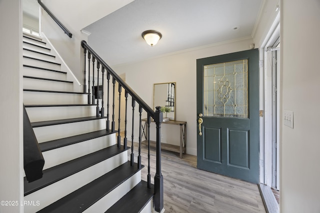 foyer with stairway, baseboards, ornamental molding, and wood finished floors