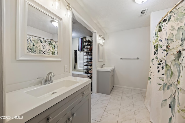 full bath featuring marble finish floor, two vanities, a sink, and visible vents