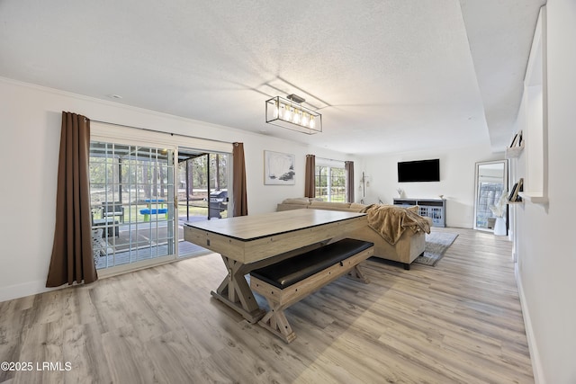 dining room with a textured ceiling, light wood-style flooring, and baseboards