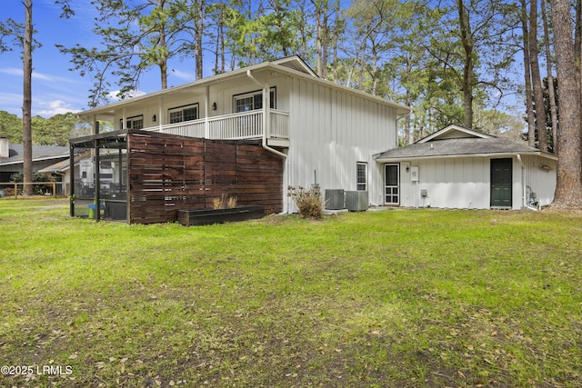 rear view of house with central air condition unit and a yard