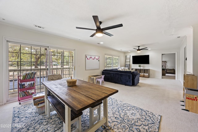 dining room featuring a ceiling fan, visible vents, light carpet, and a textured ceiling