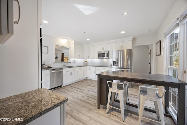 kitchen featuring appliances with stainless steel finishes, backsplash, a sink, and white cabinetry