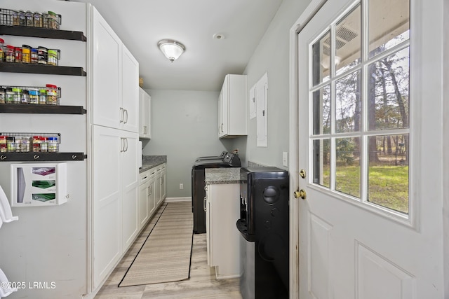 washroom featuring light wood-style flooring, washer / dryer, cabinet space, and baseboards