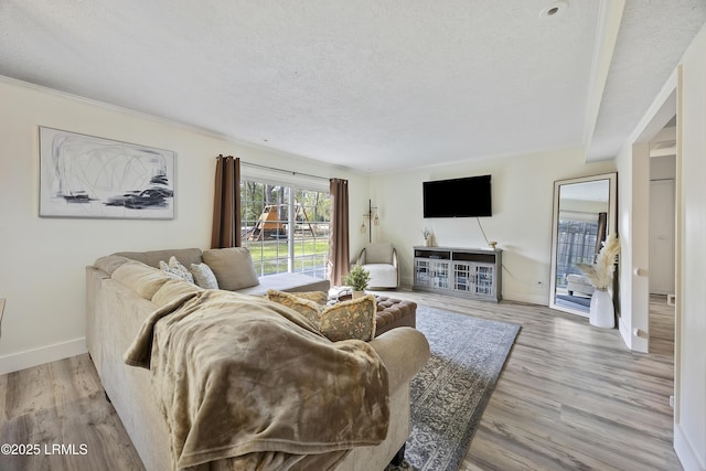 living room with a textured ceiling, light wood-style flooring, and baseboards