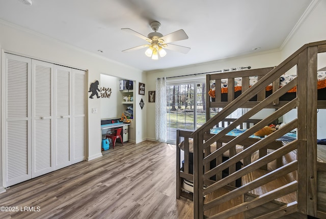 interior space with ornamental molding, a ceiling fan, baseboards, and wood finished floors