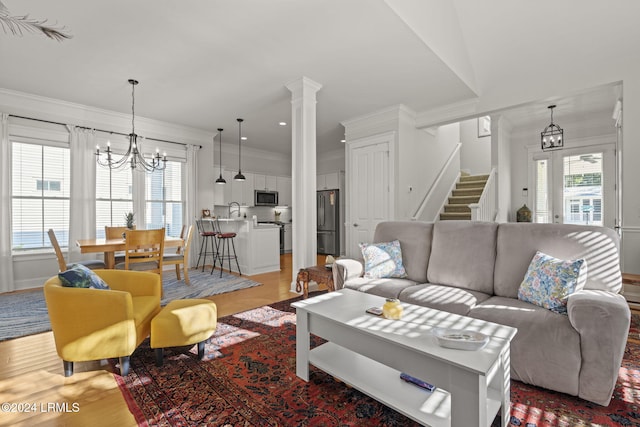 living room with ornamental molding, a chandelier, light wood-type flooring, and a wealth of natural light