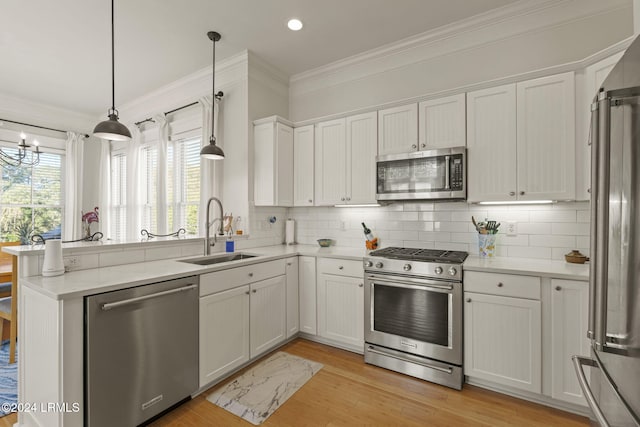 kitchen with white cabinetry, stainless steel appliances, sink, and hanging light fixtures