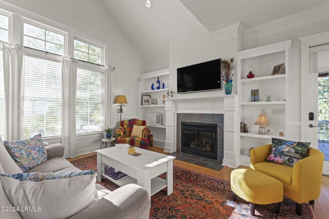 living room featuring wood-type flooring, vaulted ceiling, built in features, and a fireplace