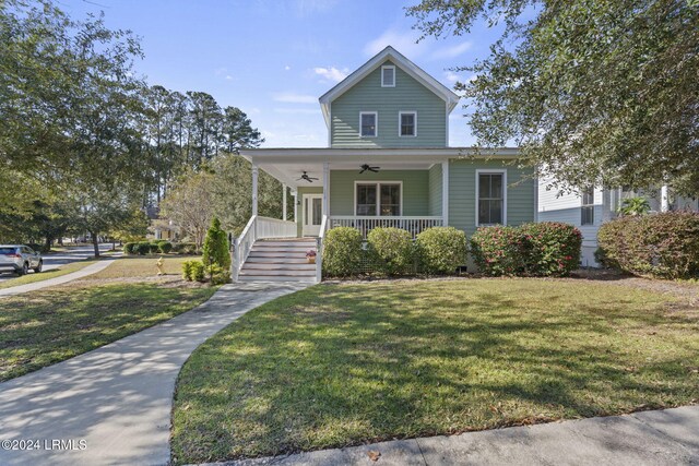 farmhouse inspired home with a front yard, ceiling fan, and covered porch