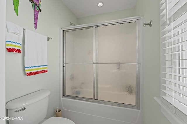 bathroom featuring bath / shower combo with glass door and toilet