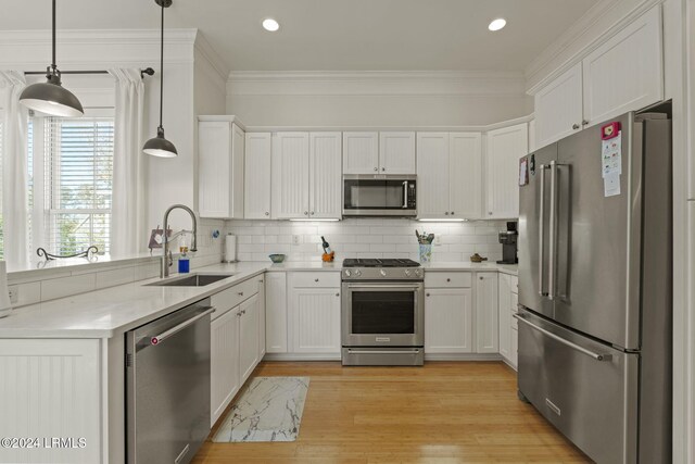 kitchen featuring sink, white cabinetry, stainless steel appliances, tasteful backsplash, and decorative light fixtures