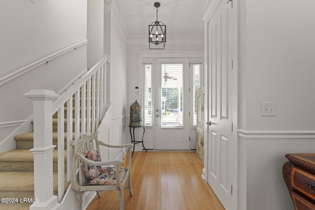 entryway with ornamental molding, an inviting chandelier, and light hardwood / wood-style flooring