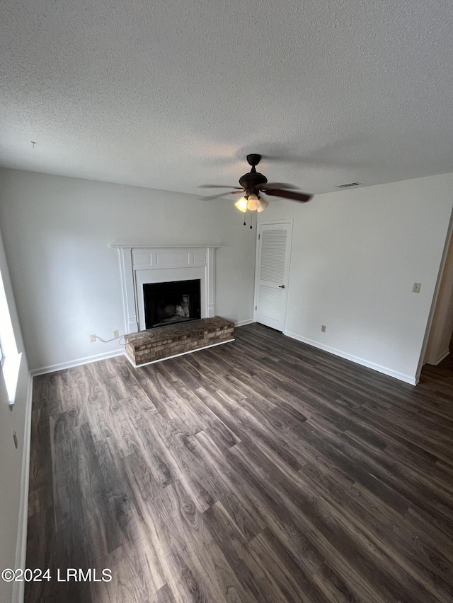 unfurnished living room featuring dark wood-type flooring, ceiling fan, and a textured ceiling