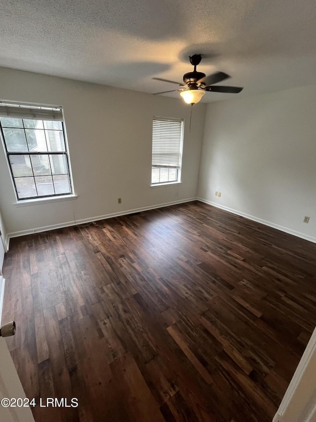 spare room with dark wood-type flooring, ceiling fan, and a textured ceiling