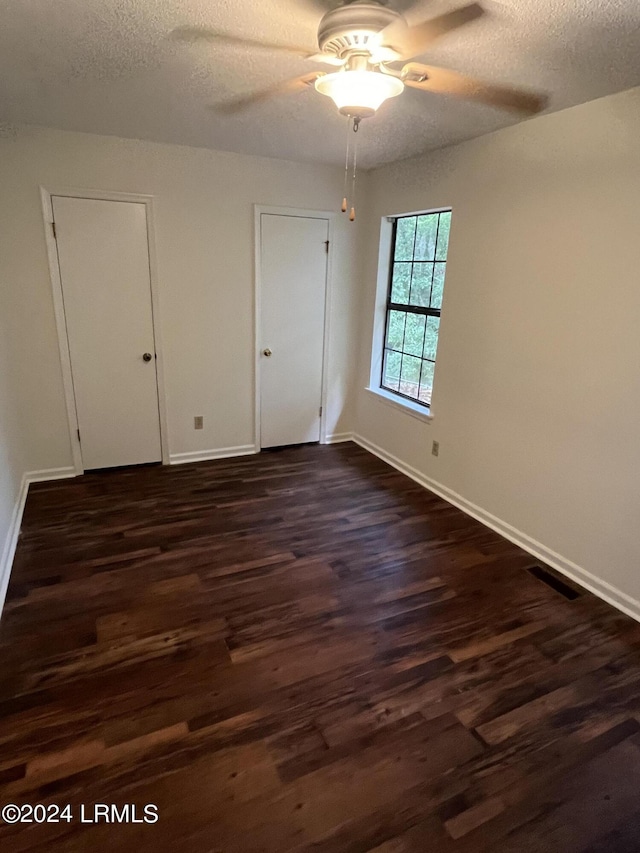 unfurnished bedroom with dark hardwood / wood-style flooring, a textured ceiling, and ceiling fan