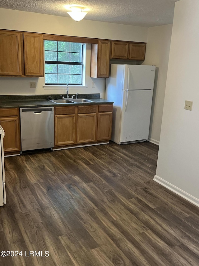 kitchen with white refrigerator, sink, stainless steel dishwasher, and dark wood-type flooring