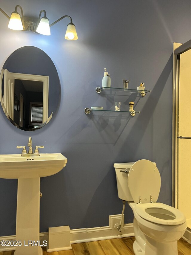 bathroom with toilet, a sink, and wood finished floors