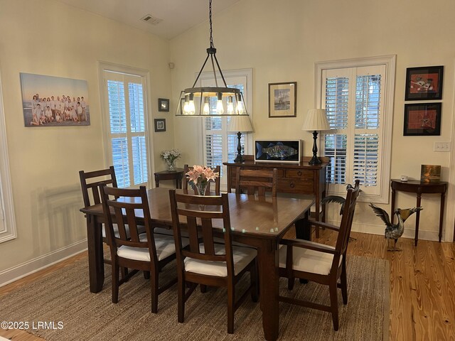 dining area with lofted ceiling, visible vents, baseboards, and wood finished floors