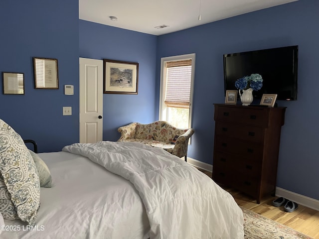 bedroom with light wood-style flooring, visible vents, and baseboards